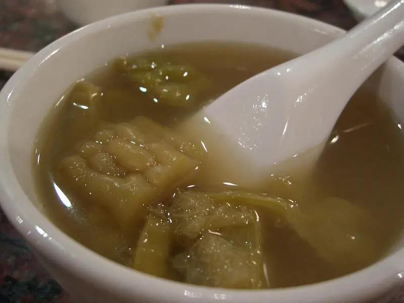 A bowl of bitter melon soup with a white spoon