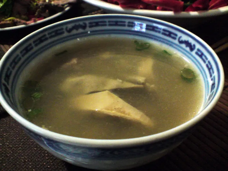 Pig stomach and white peppercorn soup in a blue-rimmed bowl